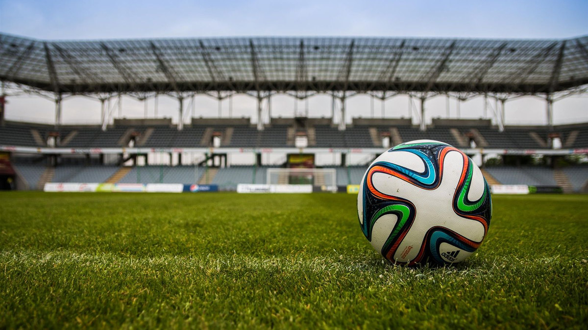Ballon de football au premier plan, pelouse et stade flous Ballon de football au premier plan, pelouse et stade flous