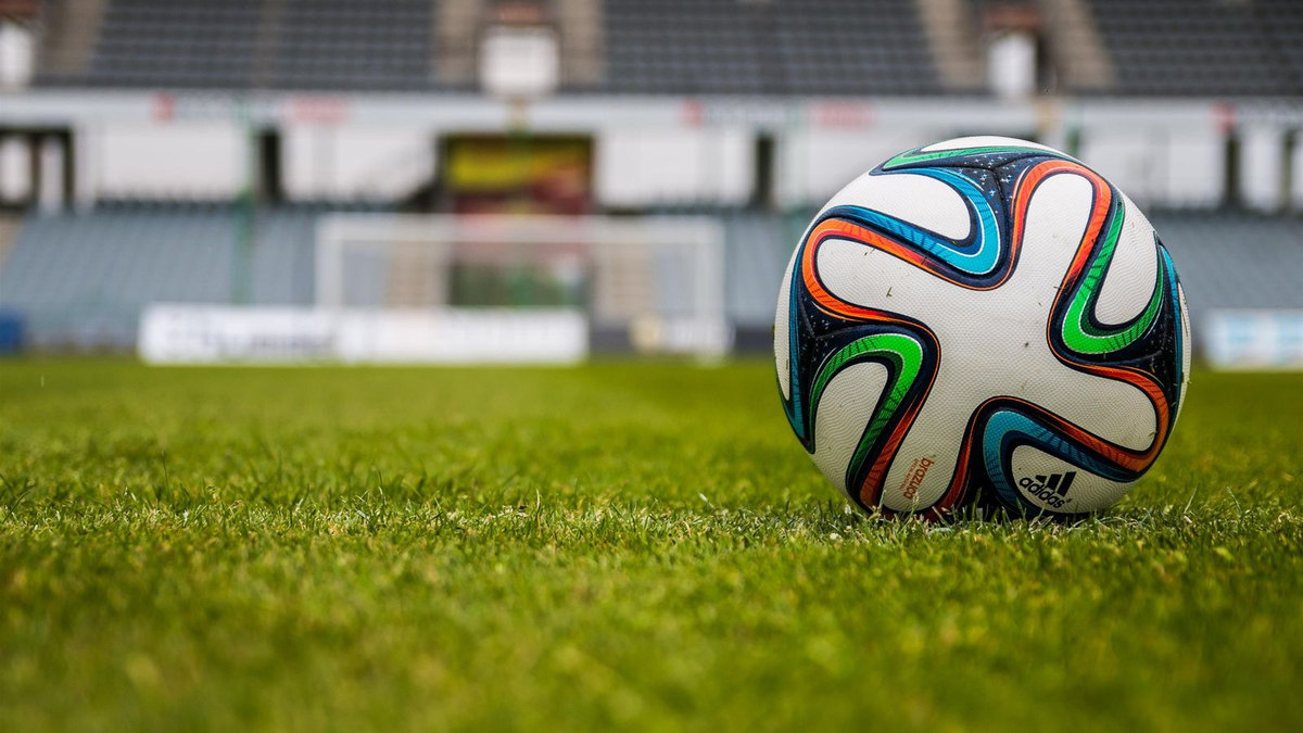 Ballon de football sur la pelouse, stade en fond Ballon de football sur la pelouse, stade en fond